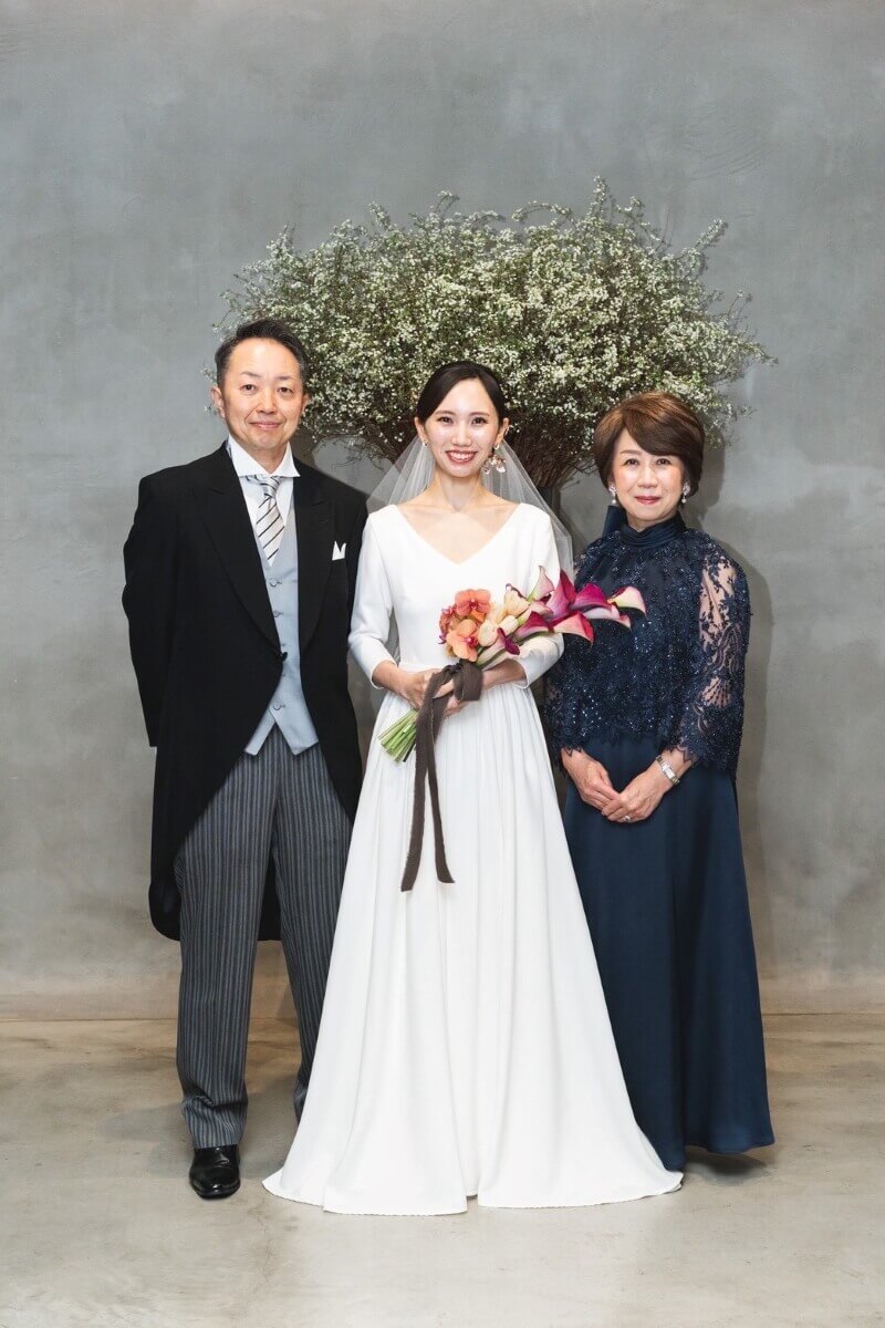 東京「IWAI表参道」にて結婚式の写真。ウエディングドレスを着た新婦様と、モーニングコート姿のお父様、ミーチェプリヴェのマザードレスを着た新婦のお母様。
